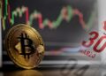 moneda de bitcoin con pantalla con grfico de precio en el fondo junto a 30 de marzo marcado en calendario