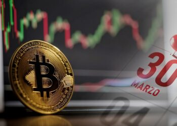 moneda de bitcoin con pantalla con grfico de precio en el fondo junto a 30 de marzo marcado en calendario