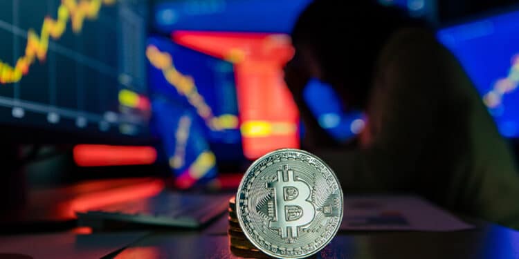 moneda de bitcoin en escritorio con trader observando graficos de precio en pantallas en la oscuridad del fondo