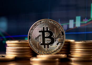 moneda de bitcoin entre monedas apiladas con grafico de precio ascendente en el fondo