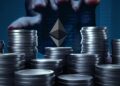 logo de ethereum sobre monedas apiladas con mano acercandose desde el fondo