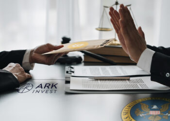 persona rechaza etf de bitcoin de ark invest con logo de la sec en la mesa