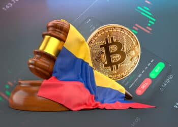 Martillo de ley junto a bitcoin y bandera de Colombia. De fondo un exchange.