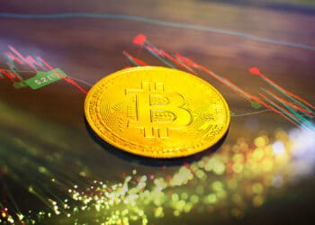 moneda de bitcoin con grafico de precio variando en el fondo