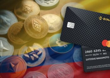 tarjeta de binance sobre bandera de Colombia con criptomonedas en el fondo