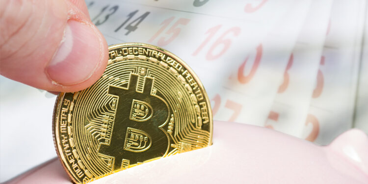 mano insertando moneda de bitcoin en alcancía con calendario pasando paginas en el fondo
