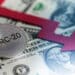 moneda de BRC-20 sobre billetes de dolares junto a flecha roja señalando disminución
