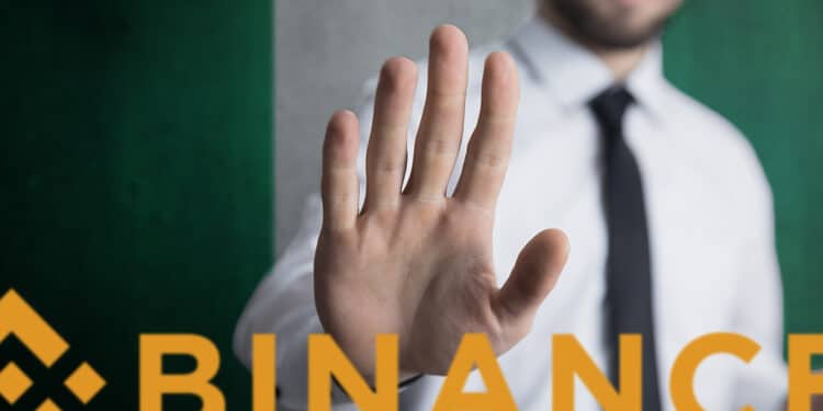 hombre haciendo señal de pare con la mano a logo de binance con bandera de Nigeria en el fondo