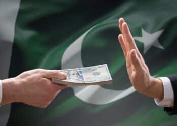 mano rechazando a mano ofreciendo billetes de dolares con bandera de pakistan en el fondo