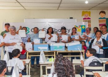 Salon de clases con maestros al frente y niños sentados en pupitres.