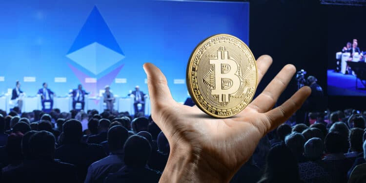 moneda de bitcoin sobre mano con conferencia de Ethereum en Francia