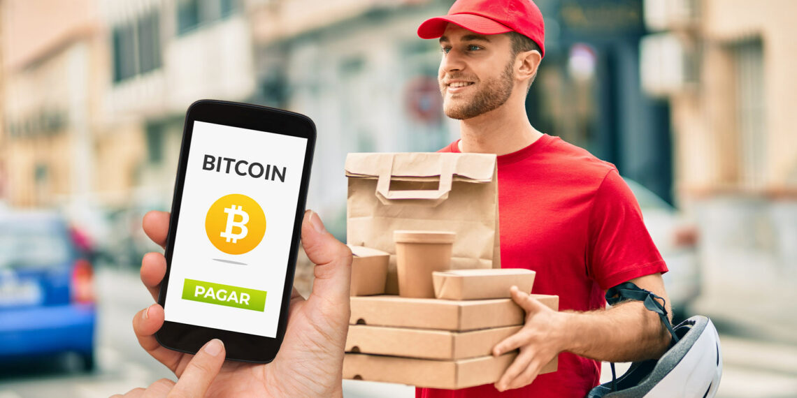 Delivery y persona pagando con bitcoin.