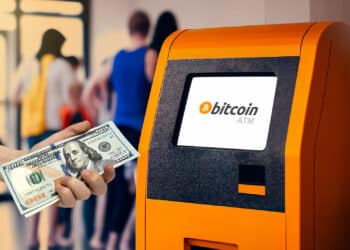 Niña introduciendo 100 dólares en un cajero automático de bitcoin.