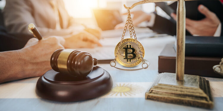 moneda de bitcoin sobre balanza junto a martillo de juez con personas redactando ley en escritorio con bandera de Argentina