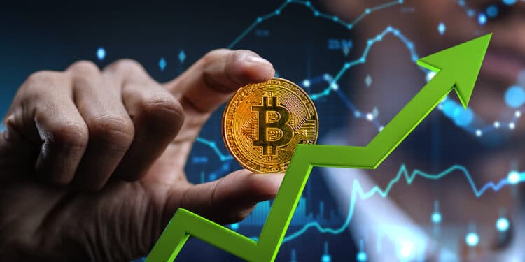 flecha señalando alza sobre mano sosteneindo moneda de bitcoin con graficos de precio digital en el fondo