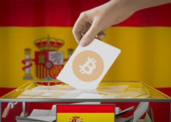 persona depositando papel de voto con logo de Bitcoin en cajeta de votaciones con bandera de España en el fondo