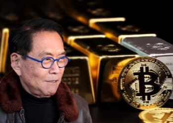 Robert Kiyosaki junto a moneda de bitcoin apoyada en lingotes de oro y plata