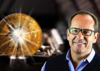 Fred Thiel con moneda de bitcoin dividiendose en el fondo