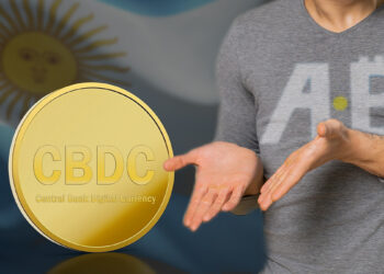 persona con logo de la ONG Bitcoin Argentina en camiseta señalando en pregunta CBDC con bandera de Argentina en el fondo