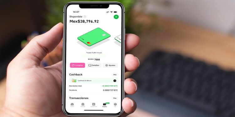Una mano masculina sostiene un teléfono celular con la aplicación de TruBit en pantalla.