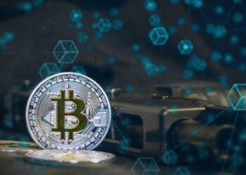moneda de bitcoin junto a arma de guego con red de bloques digitales superpuesta