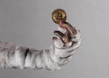 Mano de persona muerta con un bitcoin.