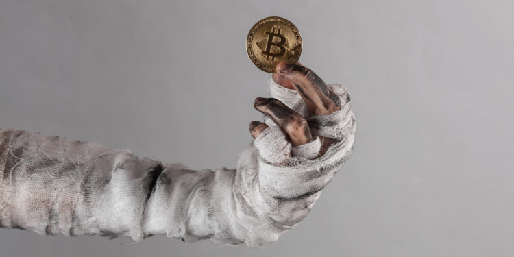 Mano de persona muerta con un bitcoin.
