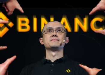 manos señalando a Changpeng Zhao, CEO de Binance con logo de la empresa detrás