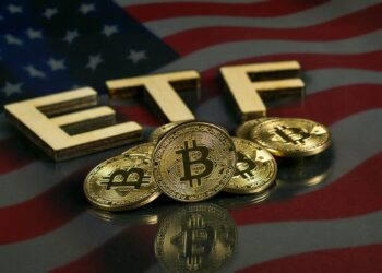 monedas de bitcoin con letras de ETF y mandera de Estados Unidos reflejada