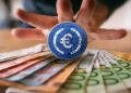 moneda de EURC sobre billetes de euto con mano detrás