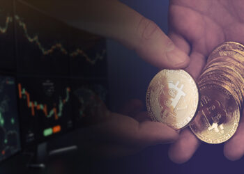 manos sosteniendo monedas de bitcoin con pantallas de exchanges a un lado