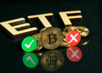 monedas de bitcoin entre simbolos de aprobacion y negación con letras de carton formando ETF en el fondo