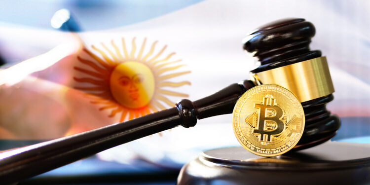moneda de bitcoin junto a martillo de juez con bandera de Argentina y persona escribiendo ley en el fondo