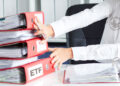 persona con logo de la SEC en camisa moviendo a un lado carpetas de archivos de ETF