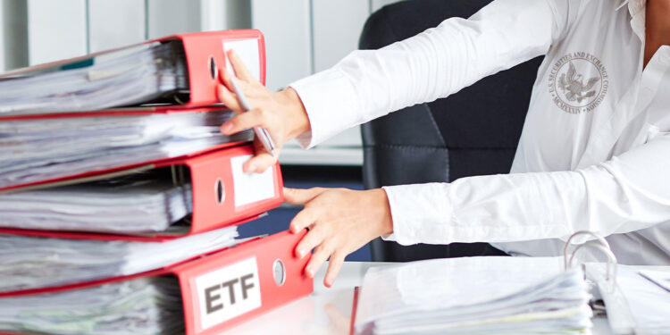 persona con logo de la SEC en camisa moviendo a un lado carpetas de archivos de ETF