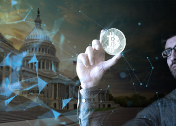 hombre sostiene y observa moneda de bitcoin con capitolio de los Estados Unidos en el fondo