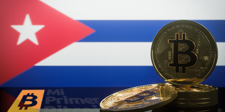 monedas de bitcoin con pantalla proyectando bandera de Cuba en el fondo y logo de Mi primer Bitcoin reflejado en mesa