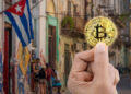 mano sosteniendo moneda de bitcoin con paisaje de Cuba en el fondo