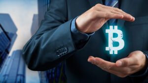 manos sosteniendo logo de bitcoin con edificios de empresa en el fondo