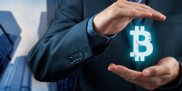 manos sosteniendo logo de bitcoin con edificios de empresa en el fondo