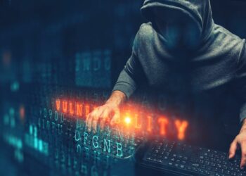 Un hacker con un teclado en un ambiente donde se lle la palabra vulnerability con códigos