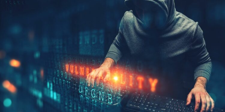 Un hacker con un teclado en un ambiente donde se lle la palabra vulnerability con códigos