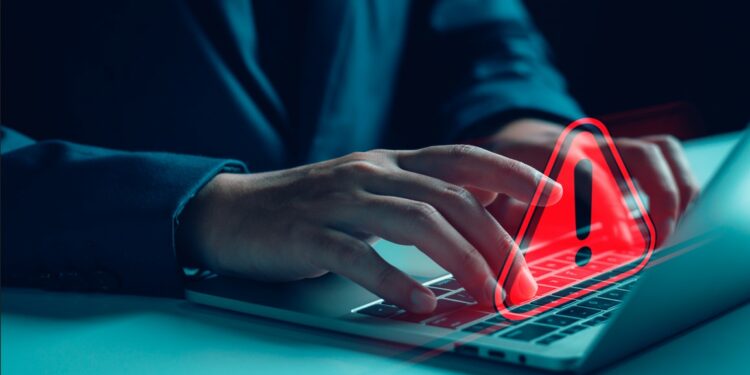 un hombre escribiendo en una computadora portátil y una señal de advertencia roja