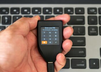 Una mano sosteniendo una Trezor durante la introducción del código PIN.