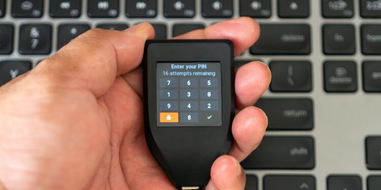 Una mano sosteniendo una Trezor durante la introducción del código PIN.