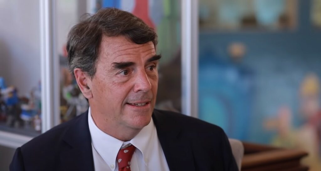 Tim Draper aparece en primer plano sentado ofreciendo una entrevista.