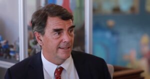 Tim Draper aparece en primer plano sentado ofreciendo una entrevista.