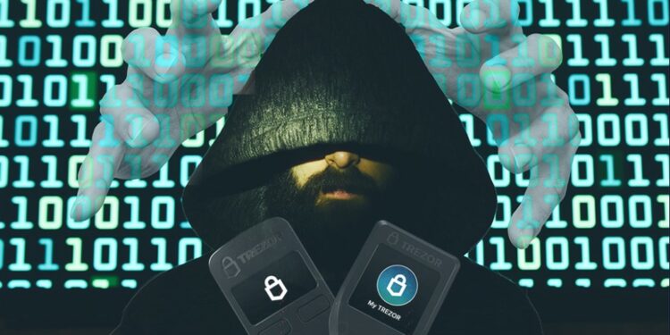 Una persona con el rosto cubierto, wallets de trezor y código al fondo