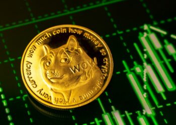 Moneda de Dogecoin sobre un tablero con un gráfico ascendente en verde