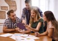 Grupo de jóvenes profesionales reunidos alrededor de una mesa de trabajo.